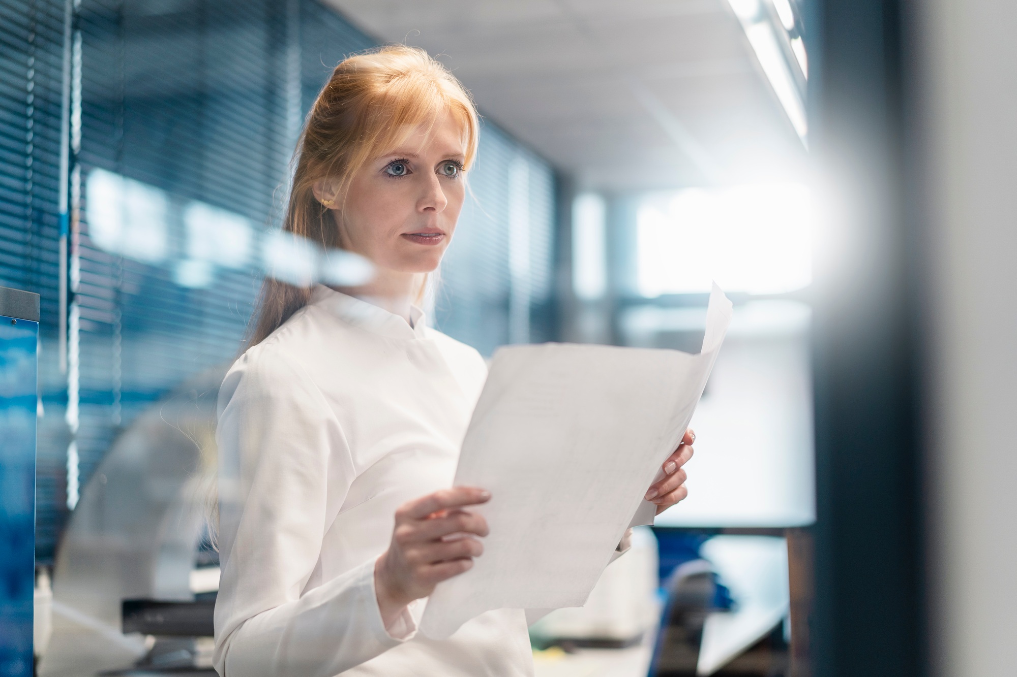 Woman wearing lab coat holding plan